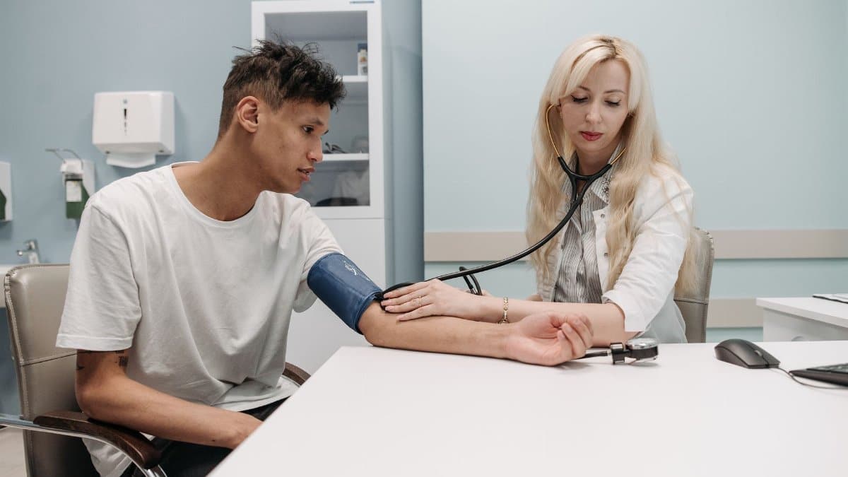 A doctor measures a patient's blood pressure in a clinic setting, focusing on healthcare and wellness.