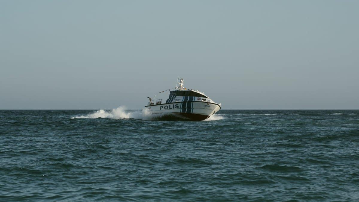 A police boat speeds across the open sea under clear skies, maintaining maritime security.