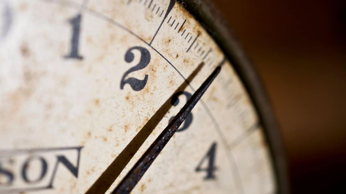 Detail of an antique scale's rusty dial with numbers and pointer, showcasing vintage charm.