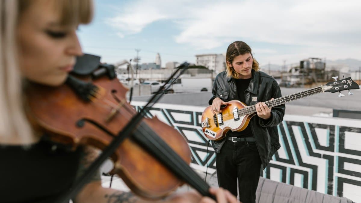 Two musicians playing guitar and violin on a rooftop, capturing a vibrant outdoor performance.