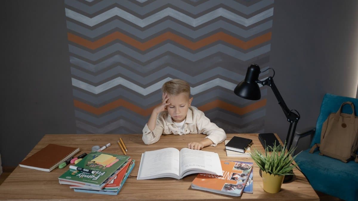 A young boy sitting at a desk, focused on his homework surrounded by school supplies.