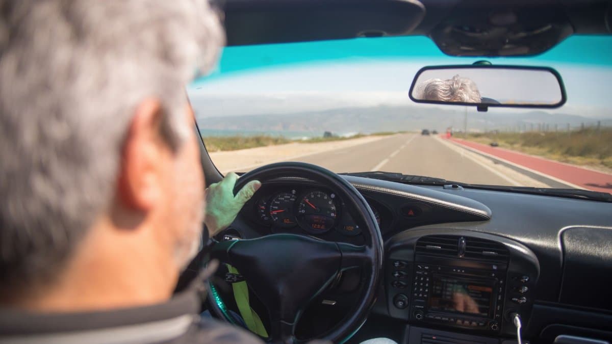A person driving a car on a scenic highway in Portugal on a sunny day.