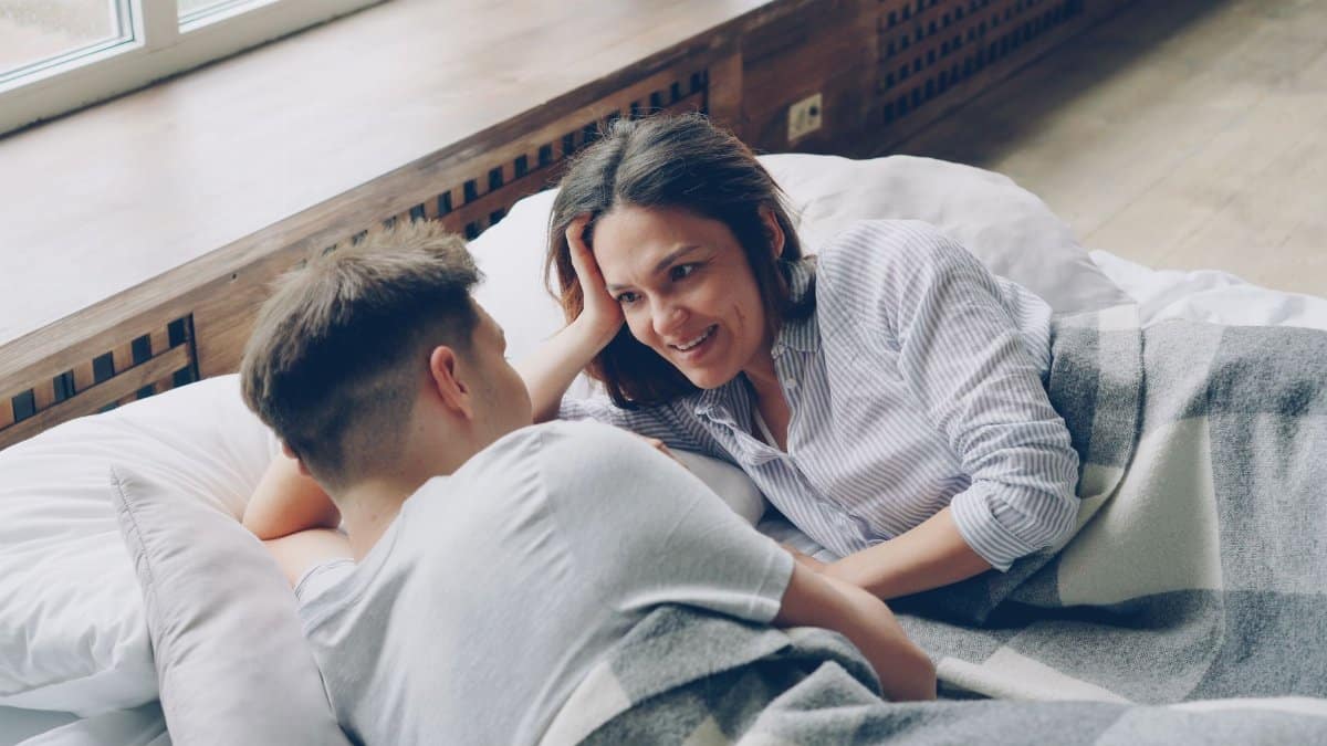A couple relaxing in bed, sharing a cozy moment filled with warmth and intimacy.