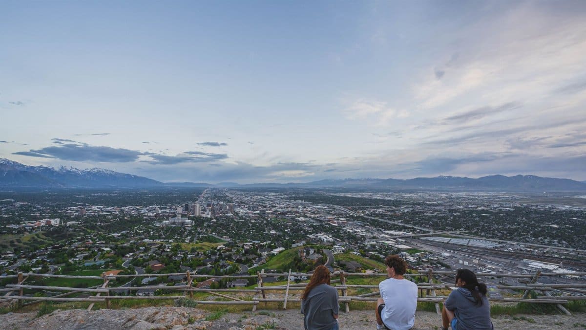Group of friends sitting on a hill enjoying the panoramic cityscape view.