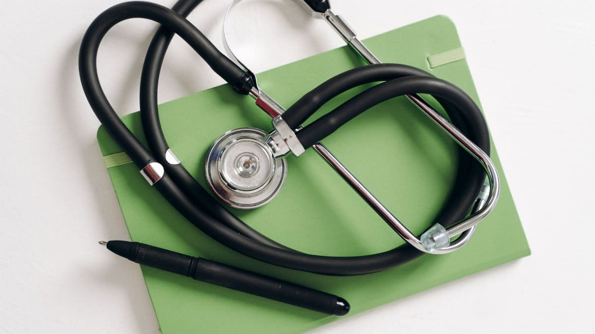 Top view of a stethoscope and pen on a green notepad, ideal for medical and educational themes.