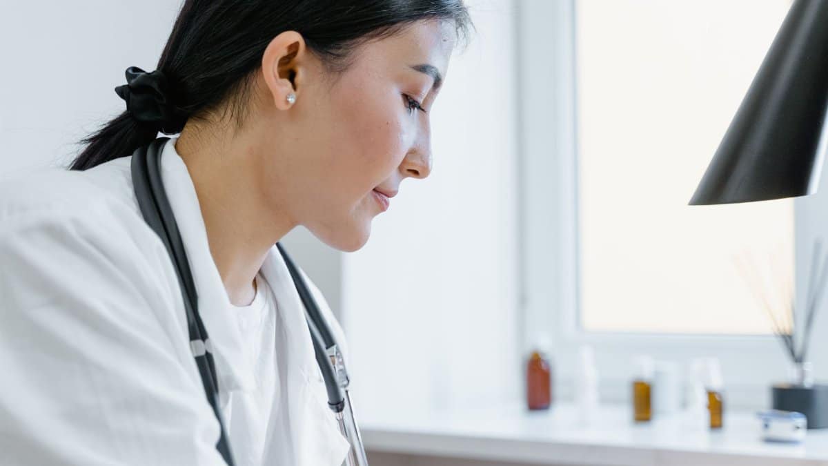 Close-up of an Asian female doctor working in an office setting, with medical tools visible.