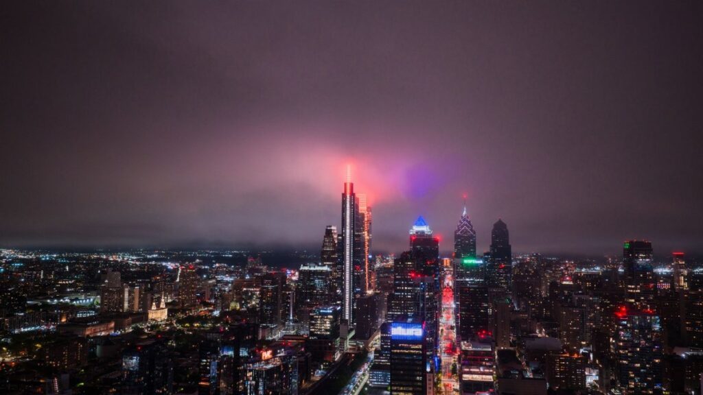 Aerial view of the Philadelphia skyline at night with vibrant city lights illuminating the skyscrapers.