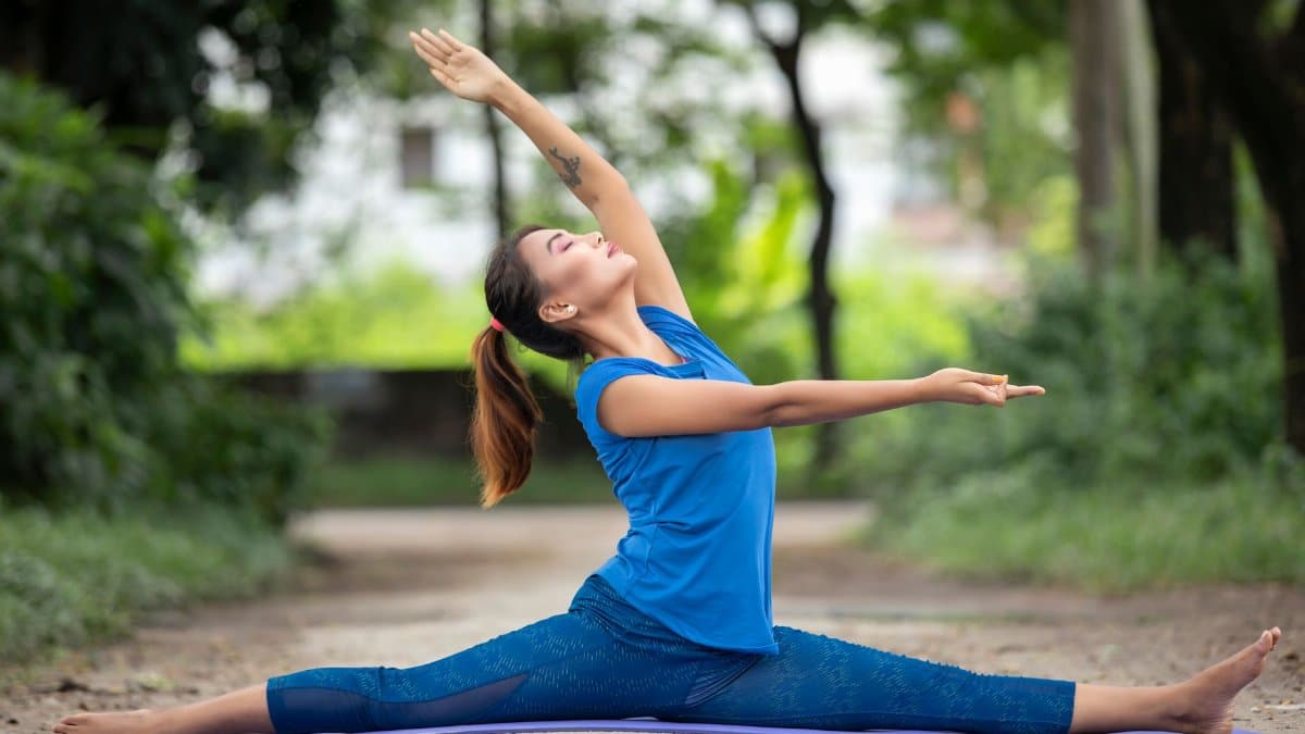 Woman practicing yoga in a park, showcasing flexibility and balance in a serene outdoor setting.