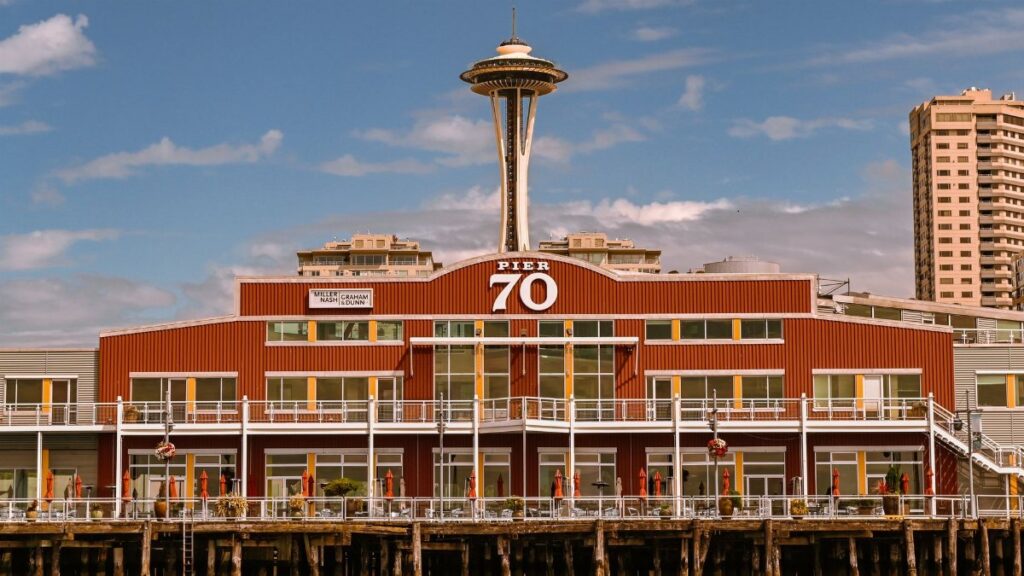 View of Seattle's iconic Space Needle behind Pier 70 against a clear blue sky.