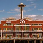 View of Seattle's iconic Space Needle behind Pier 70 against a clear blue sky.