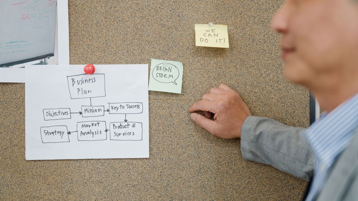 Office worker analyzing business plan on corkboard, boosting teamwork and strategic planning.