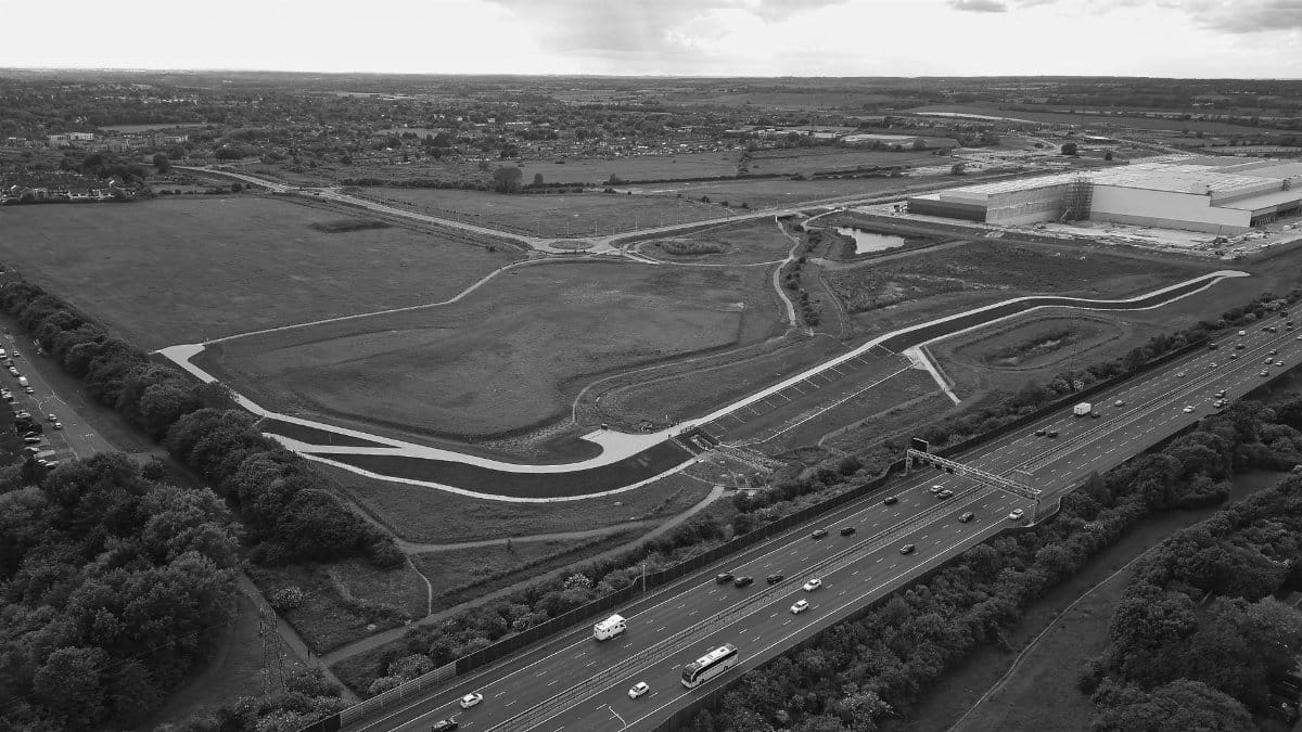 Black and white aerial view of highway, fields, and industrial district.
