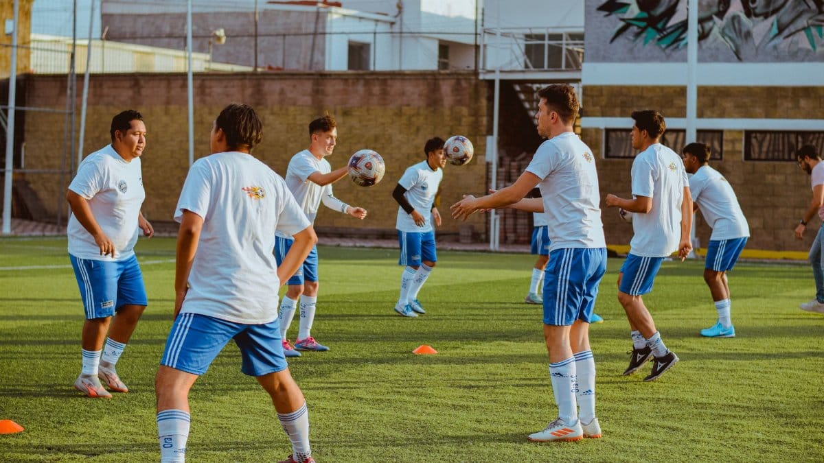 Group of young men practicing soccer on an outdoor field.