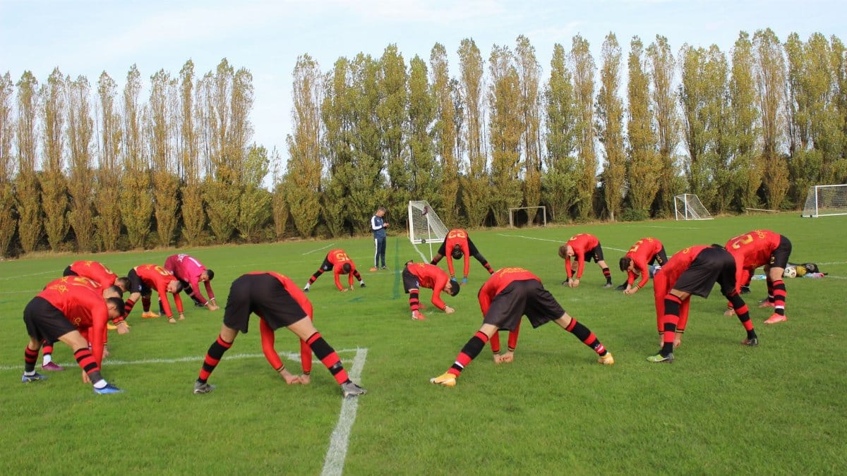 Soccer team stretching on the field before a game on a clear day, preparation for the match.