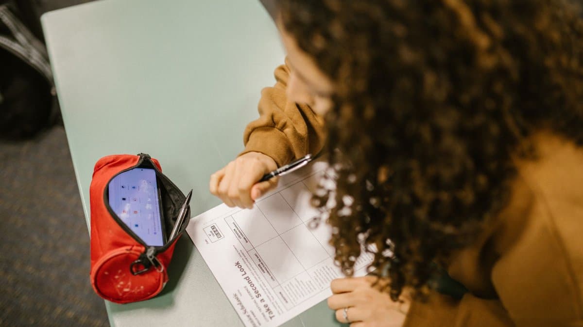 A student using a smartphone hidden in a pen case during an exam.
