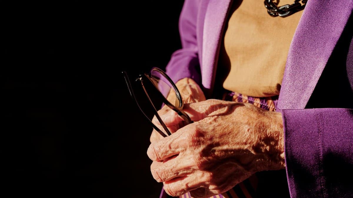 A senior adult's wrinkled hands holding eyeglasses, showcasing age and elegance.