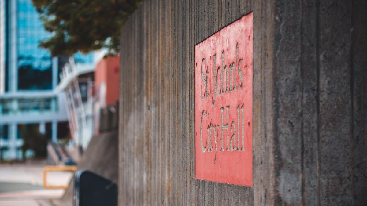 Concrete wall with a St. John's City Hall sign, showcasing urban texture in selective focus.