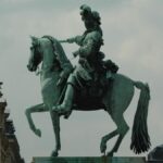 Majestic equestrian statue of Louis XIV against historic French architecture.