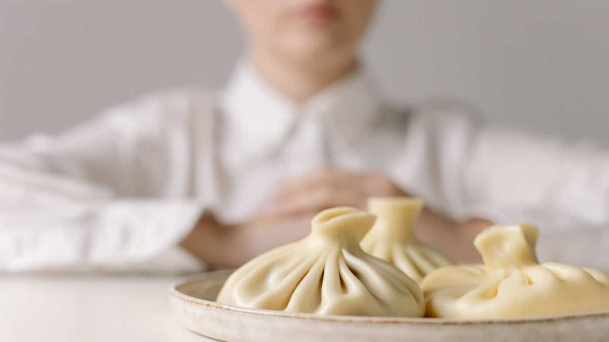 Delicious traditional dumplings on a plate with a blurred background of a person in a white shirt.
