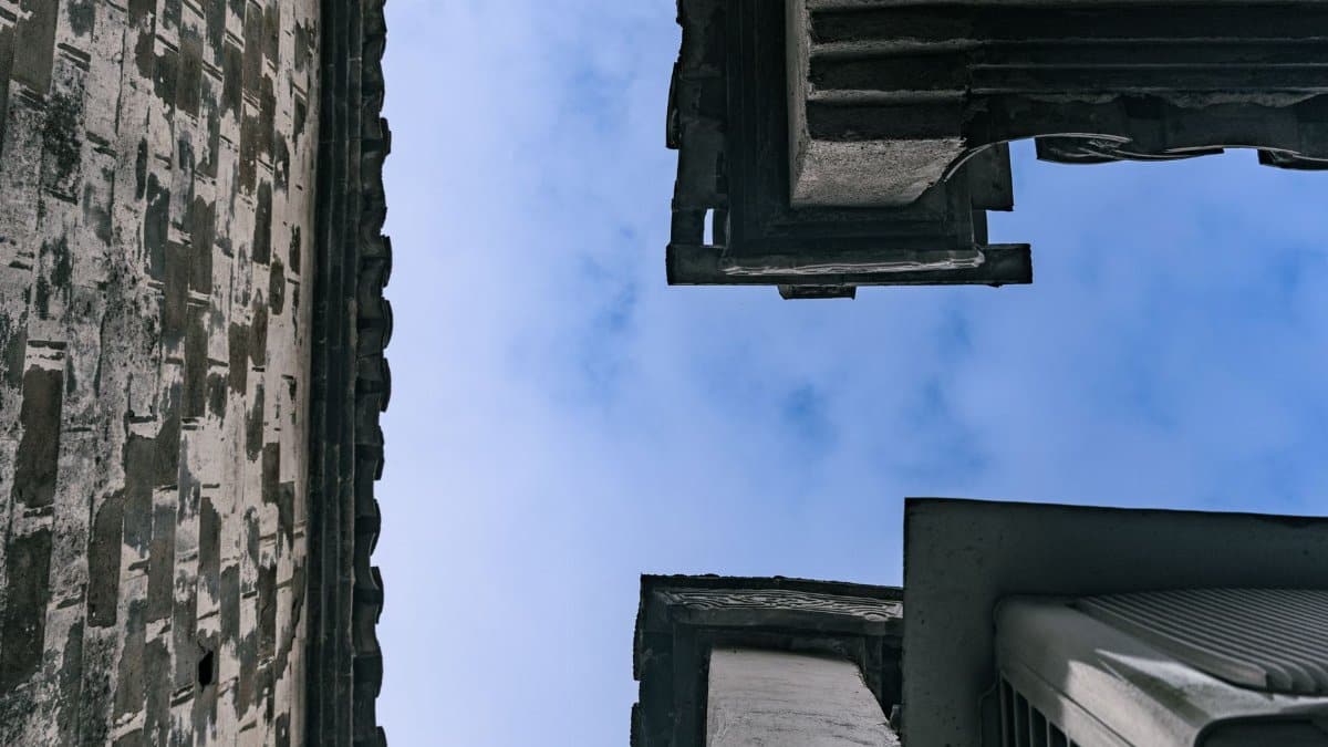 View skyward between vintage buildings showcasing unique architectural design.