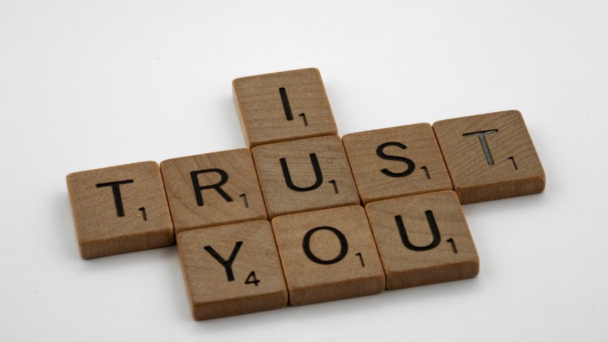 Close-up of Scrabble tiles arranged to spell 'I Trust You' on a white background, symbolizing trust.