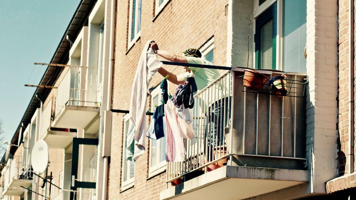 A person hangs laundry on a sunny balcony in Amersfoort, Netherlands, showcasing urban lifestyle.
