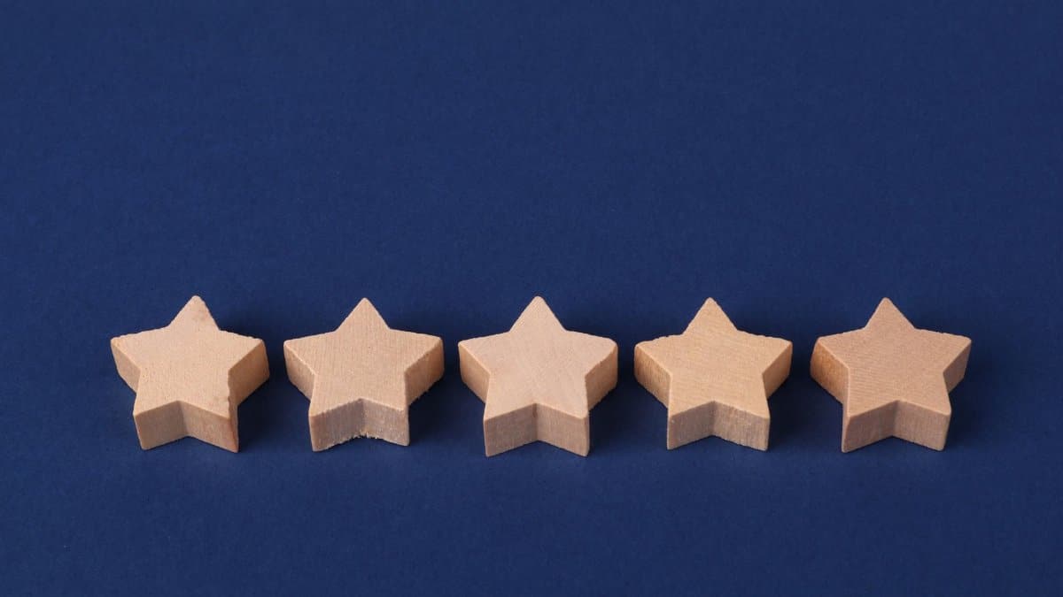 Five wooden stars on a blue background representing a rating system or evaluation concept.