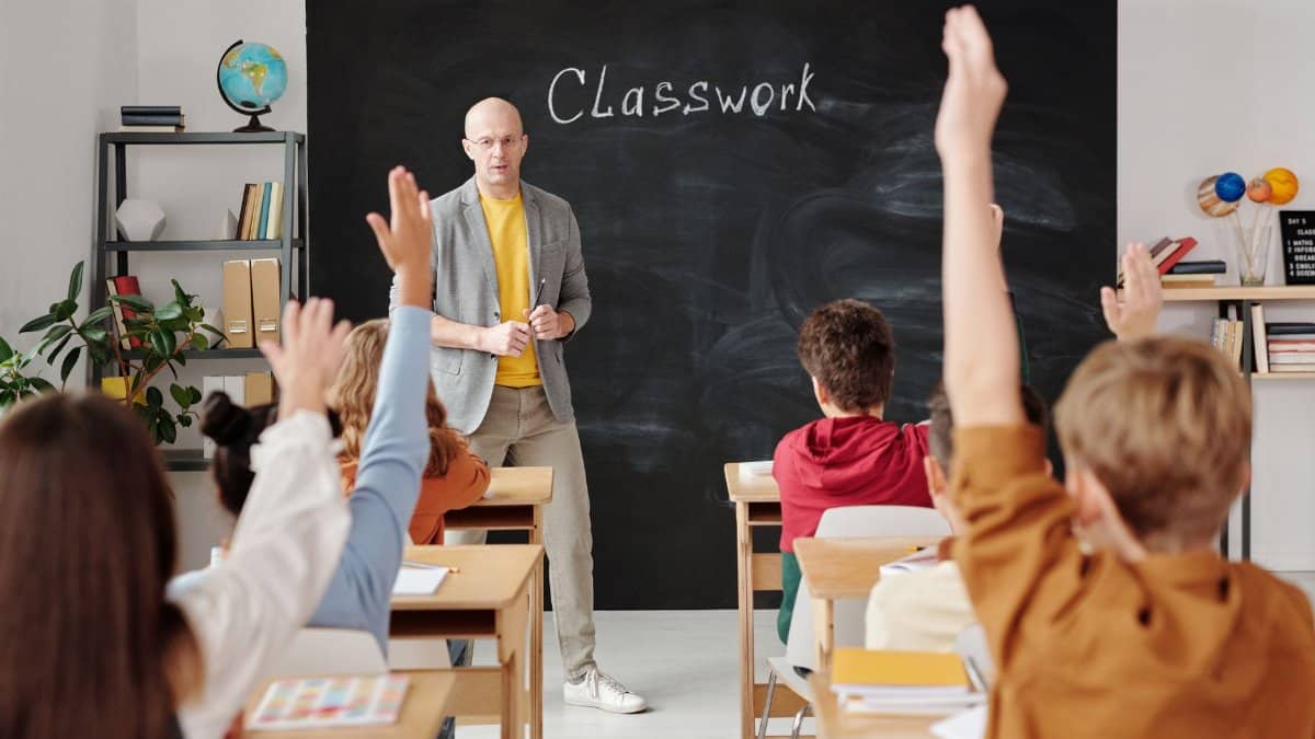 A teacher interacts with diverse students in a classroom, engaging them in active learning.
