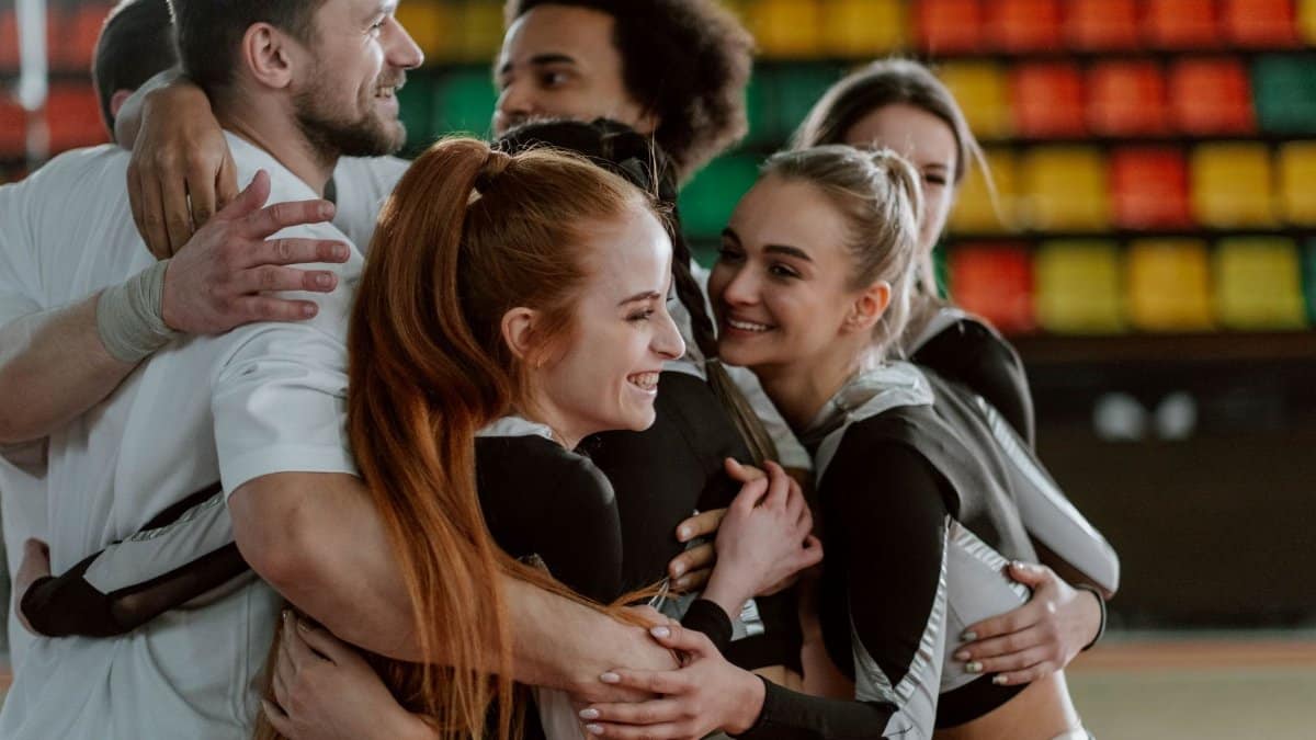 A joyful group of cheerleaders hugging, celebrating a successful performance indoors.