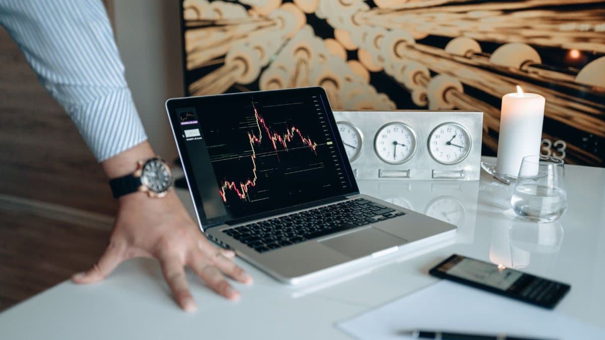 A contemporary desk setting with technology gadgets and a laptop displaying a stock chart.