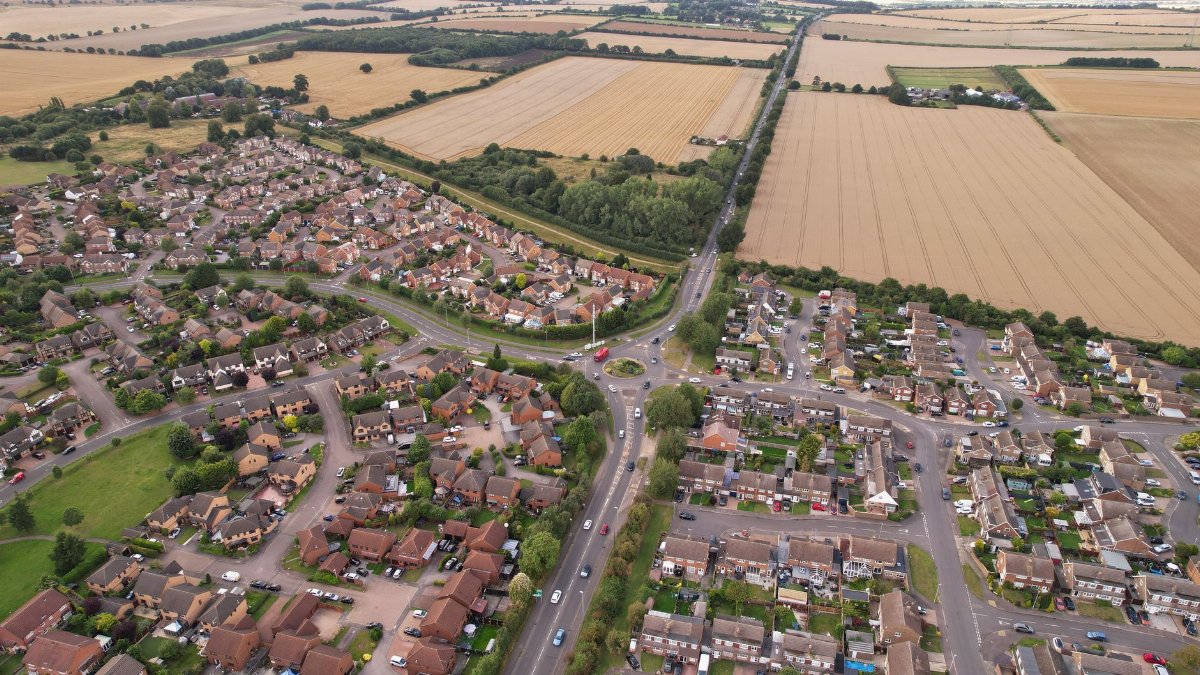 Aerial photograph showcasing the residential area and countryside of Luton, England during summer.