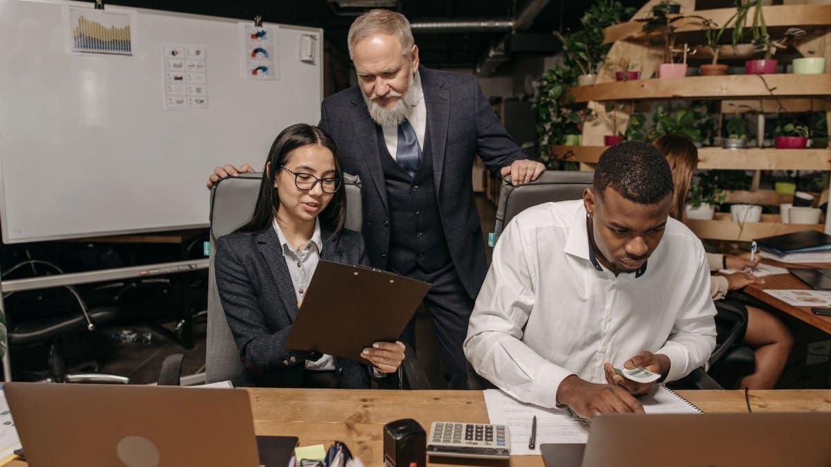A diverse group of professionals working in a modern office with laptops and documents.