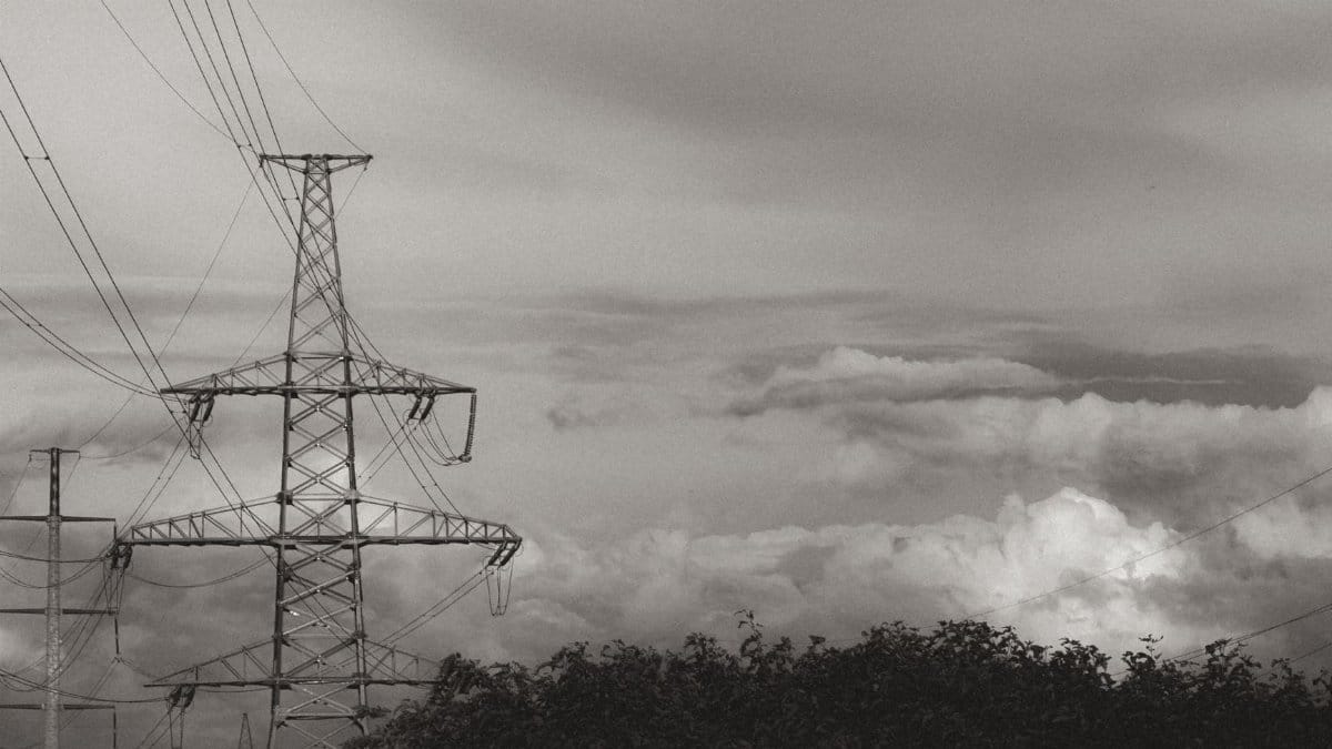 Black and white image of power lines against a dramatic cloudy sky, conveying industrial strength.
