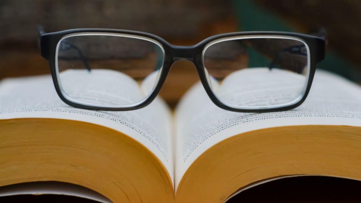 Eyeglasses resting on an open book, highlighting reading and education theme.