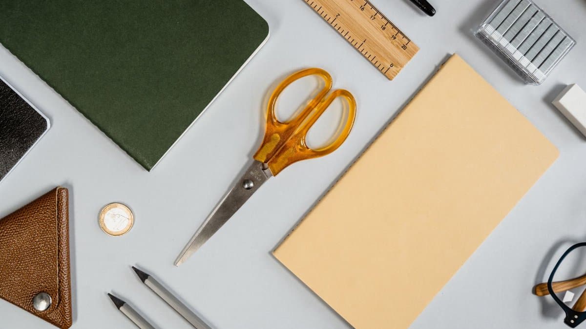 Flat lay showcasing various office supplies including scissors, notebook, ruler, and pencil.