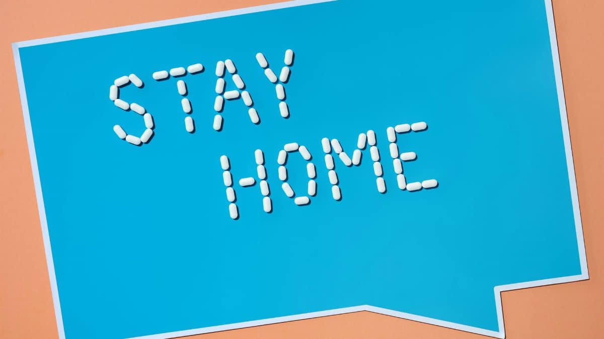 Creative conceptual image showing 'Stay Home' message made of pills on blue background.