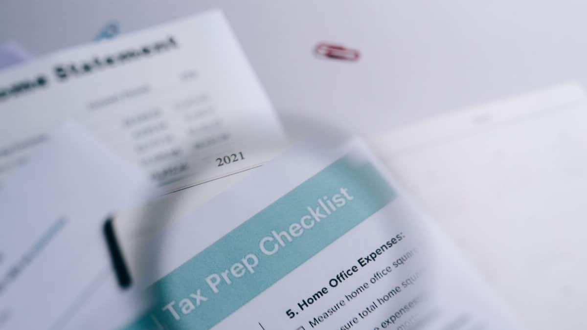 Close-up of tax preparation checklist and income statement with paperclips.