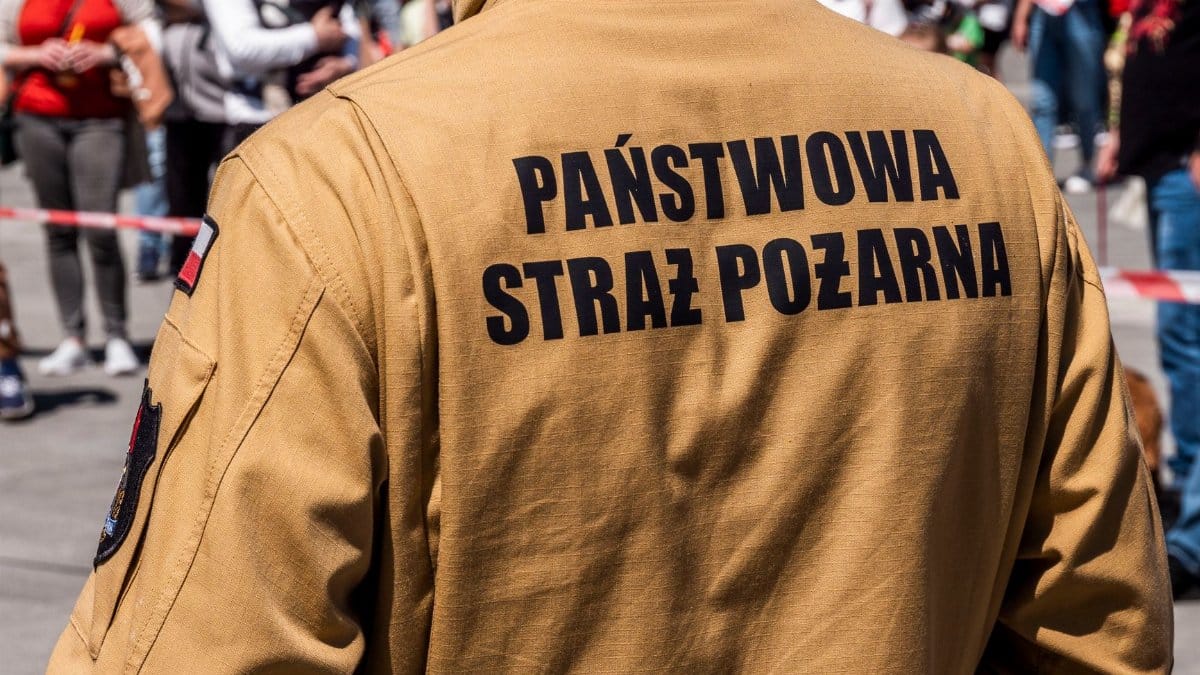 A Polish firefighter in uniform at a public event, surrounded by a crowd.