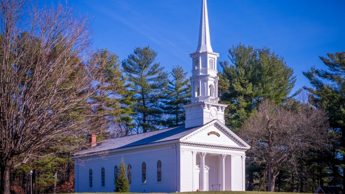 Classic white church with steeple surrounded by trees in Sudbury, Massachusetts.
