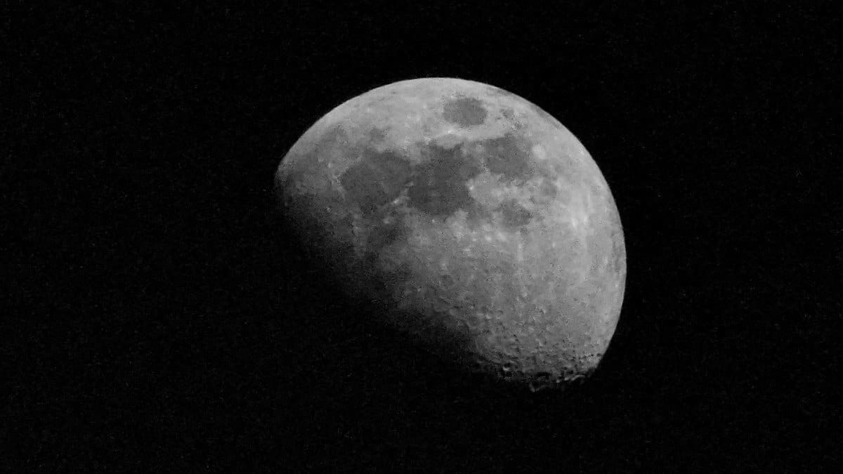 Detailed photo of the moon in a high contrast black sky, capturing lunar surface features.