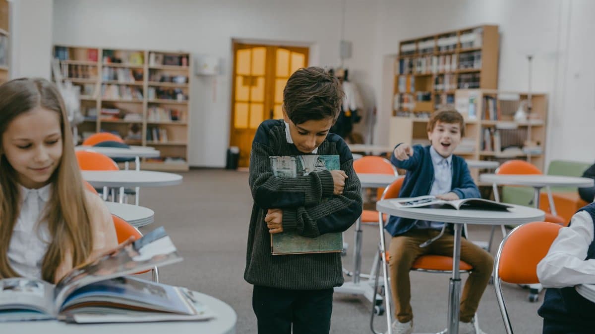 A boy being bullied by classmates in a school classroom setting.
