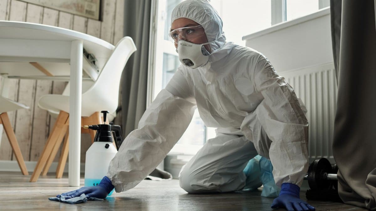 Person in full protective suit cleaning a floor, showcasing safety measures.
