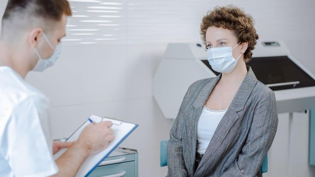 Doctor and patient wearing masks during a medical consultation in a modern healthcare setting.
