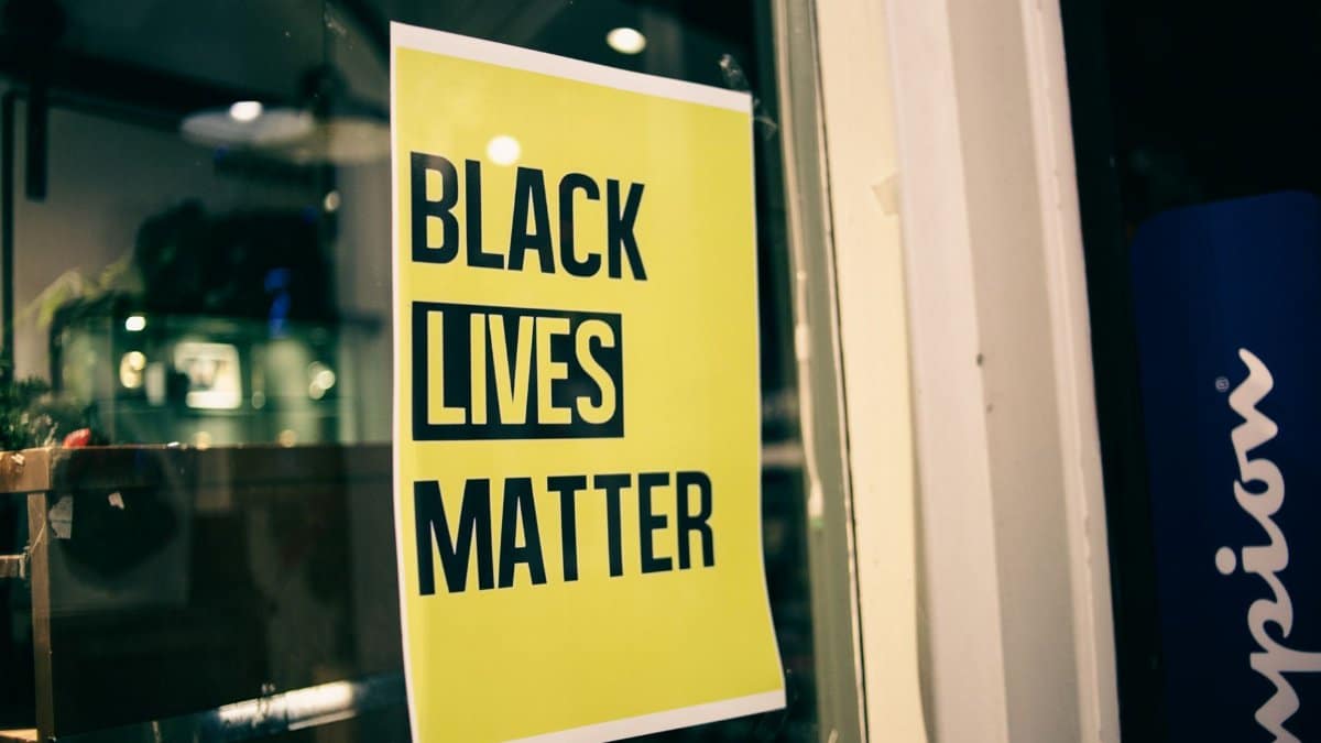 Colorful yellow rectangular shaped signboard with inscription Black Lives Matter on glass door