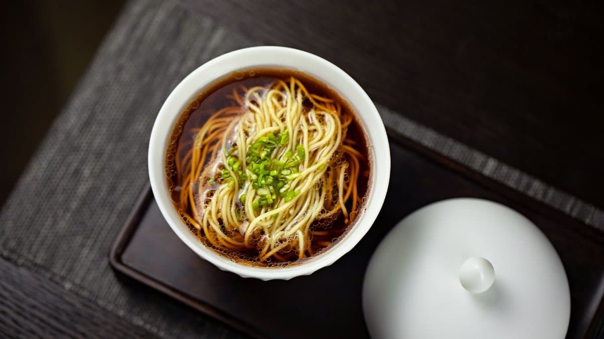 A gourmet bowl of noodle soup garnished with fresh chives, perfect for food photography enthusiasts.
