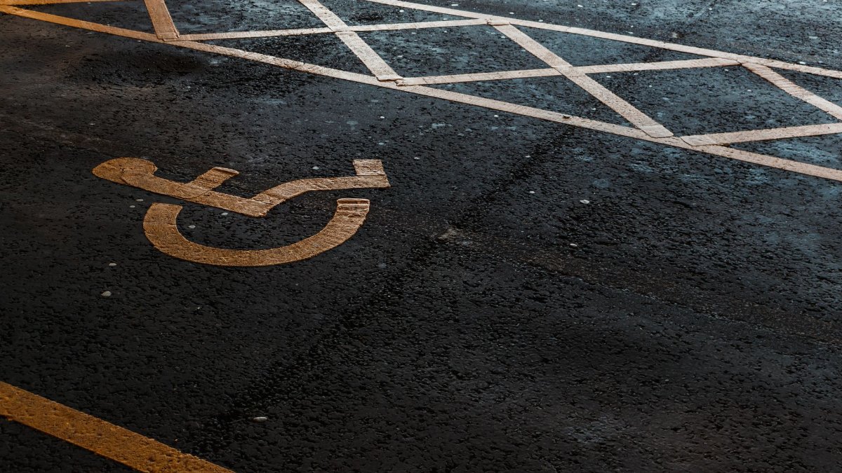 Close-up of an accessible parking symbol on a dark asphalt surface, featuring evening light.
