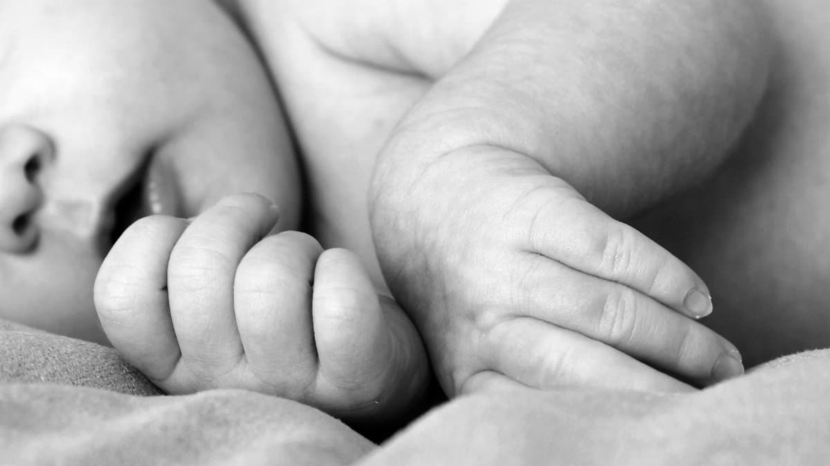 Black and white close-up of a newborn baby's hands, symbolizing innocence and new life.