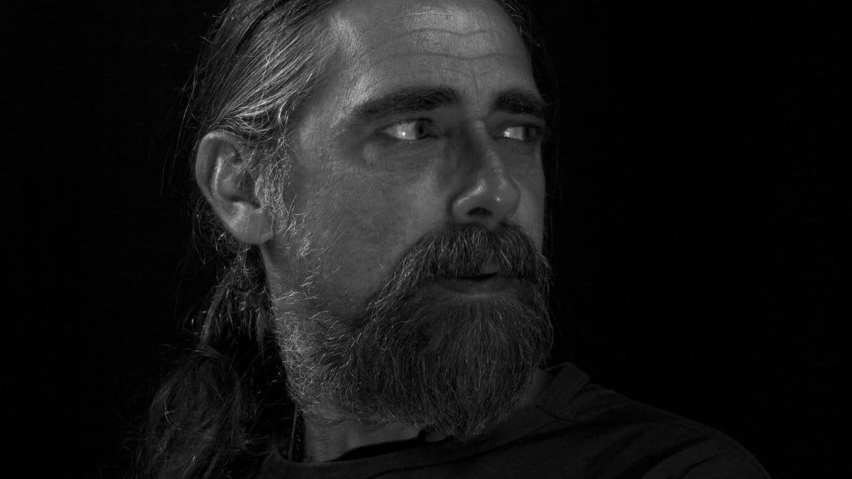 Black and white portrait of a serious bearded man looking thoughtfully to the side.