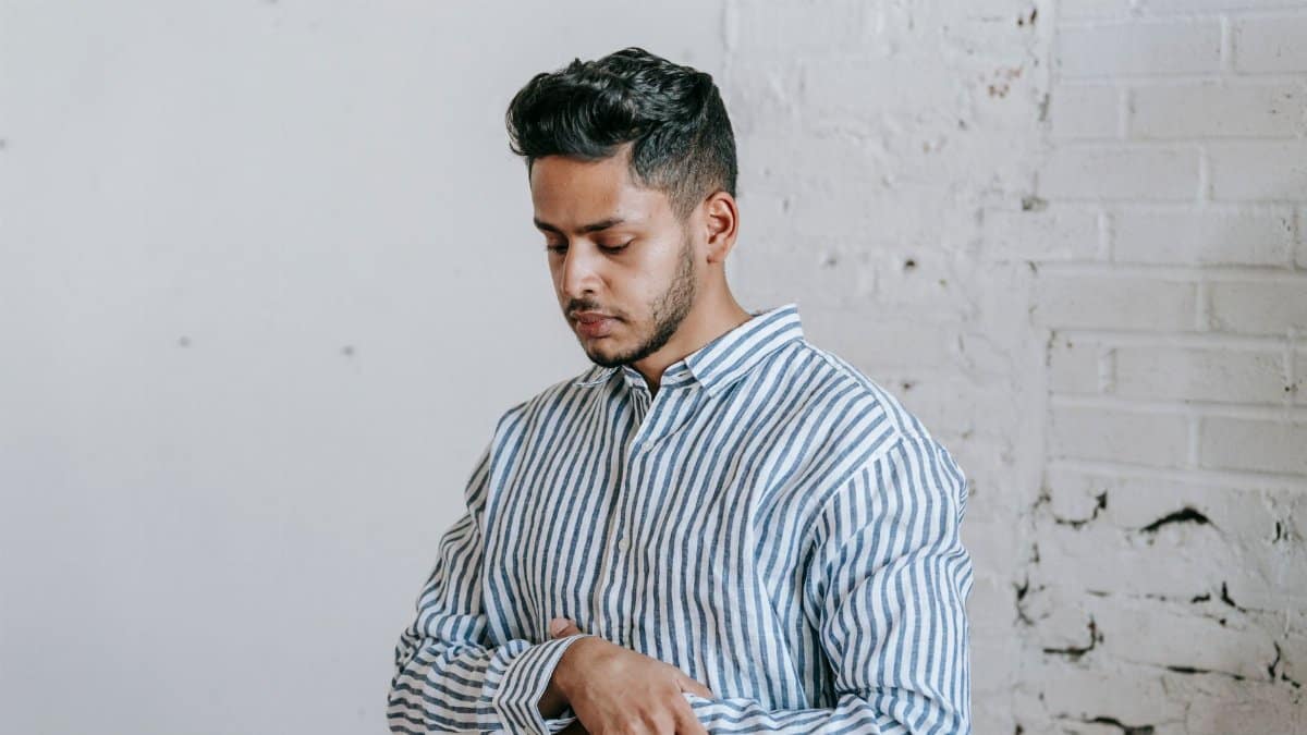 A young man performing salah while standing in a peaceful indoor setting.