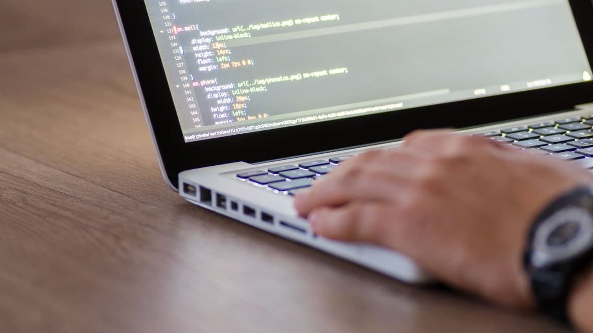 Person coding on a laptop with HTML code on screen, showcasing development work.